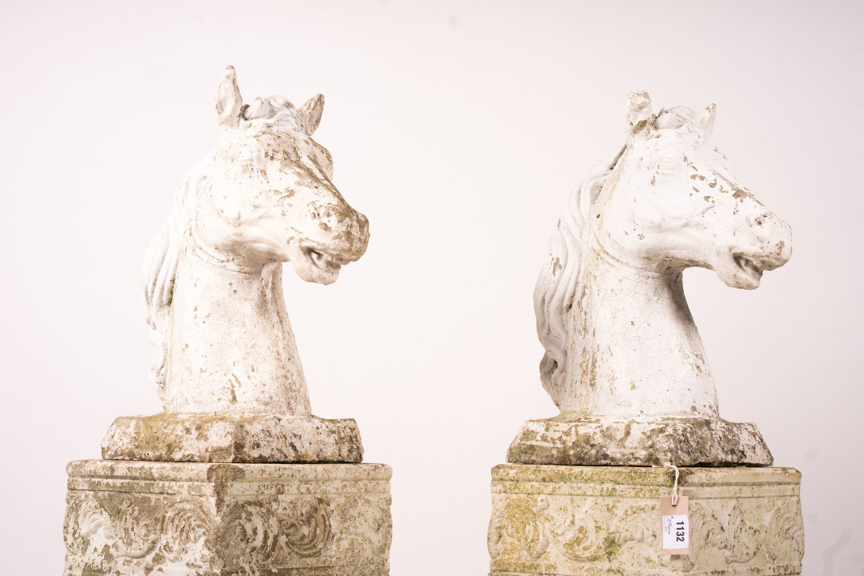 A pair of reconstituted stone horse's heads on plinth bases in the style of Austin and Seeley, height 104cm